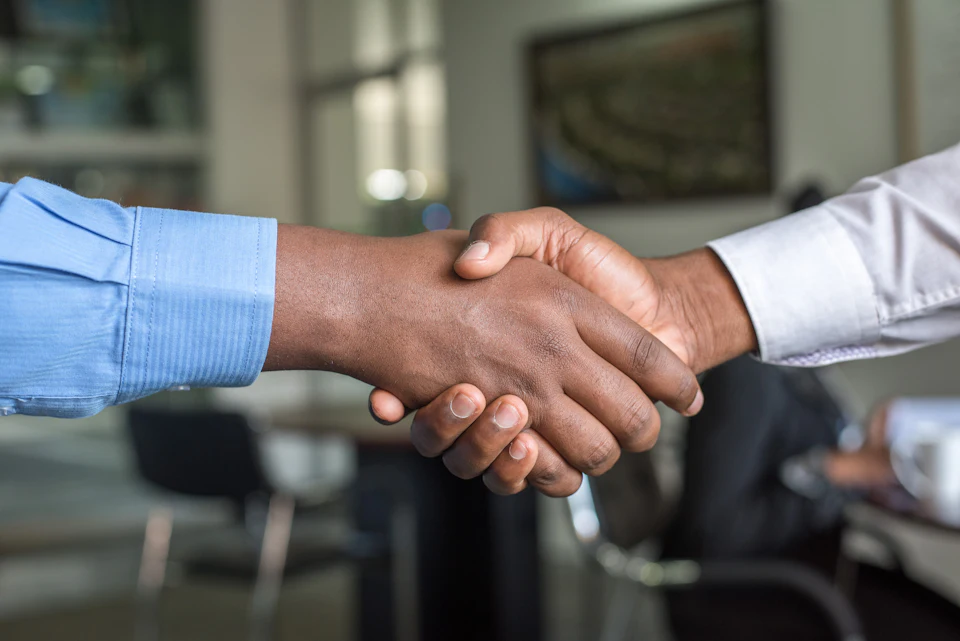 Two people shaking hands across a table